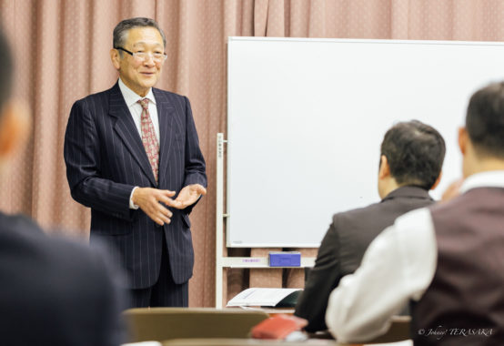 経営再建について語る講師が、受講者を前に穏やかな表情で説明している講話の様子