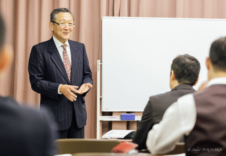 経営再建について語る講師が、受講者を前に穏やかな表情で説明している講話の様子