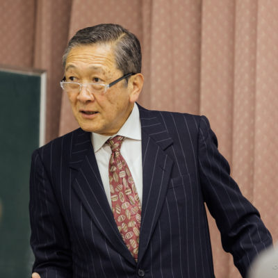 講師が真剣な表情で受講者に語りかけ、経営の課題について説明している講話の様子