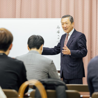 経営者向け勉強会にて、ホワイトボードを前に真理と経営の在り方を語る講師の姿